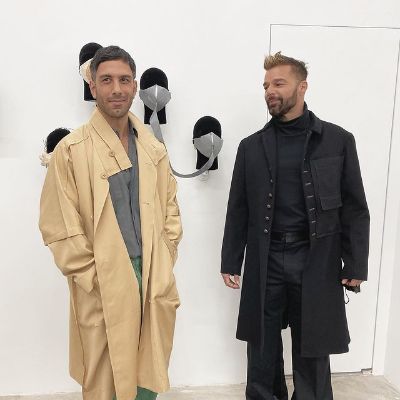 Ricky Martin is looking at Jwan Yosef as there are faces wearing masks in the background.